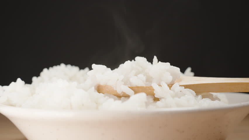 Rising Steam Over a Bowl of Freshly Cooked White Rice as a Wooden Spoon Scoops Up Soft and Moist Grains, Creating a Warm and Comforting Scene