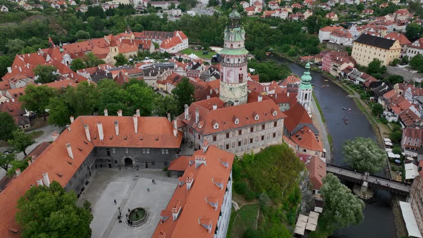Český Krumlov, South Bohemia, Czechia, July 2023. Drone parallax orbit to the right above the historic medieval Castle tower with the Vltava river and tourists rafting in canoes in the background.