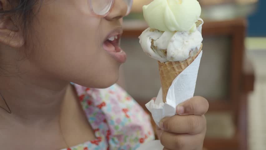 A young child savors a colorful ice cream cone at a local shop..