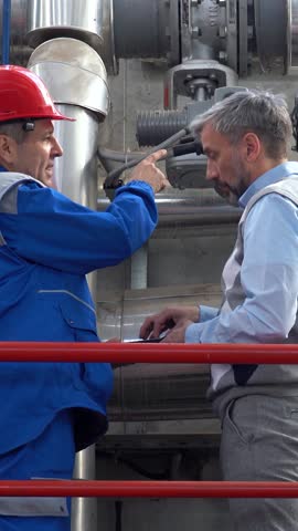 Production Manager and Maintenance Technician Discuss Production Process in a Factory. Middle-aged worker in protective workwear using digital tablet and talking to supervisor. Energy Industry.