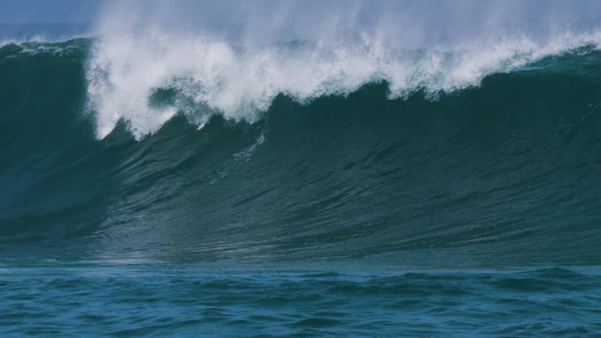 CLOSE UP, SLOW MOTION: Powerful and empty ocean wave crests and breaks under clear blue skies. Perfect shape and offshore spray coming off the lip reflect perfect surf conditions at Canary Islands.