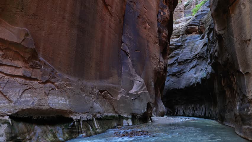 Static shot of the Narrows in Zion National Park. Tall vertical sandstone walls rise straight out of the Virgin River at the start of the Wall Street section of this popular hiking destination. 