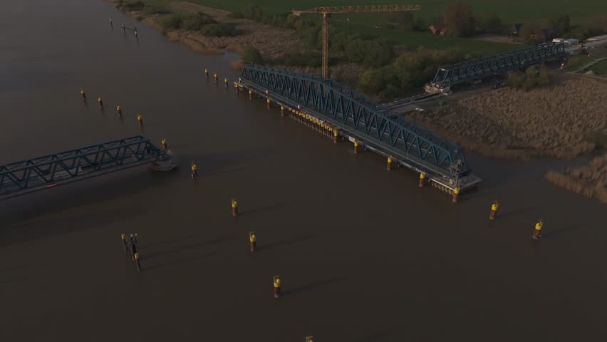 Aerial shot of the new Friesenbrücke railway project near Leer, Germany, at sunset. Massive infrastructure site near Dutch border, crossing the Ems River. Bridge and construction site in golden light.