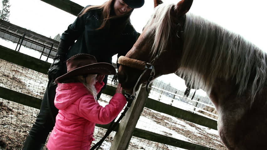 little girl in a cowboy hat petting horse