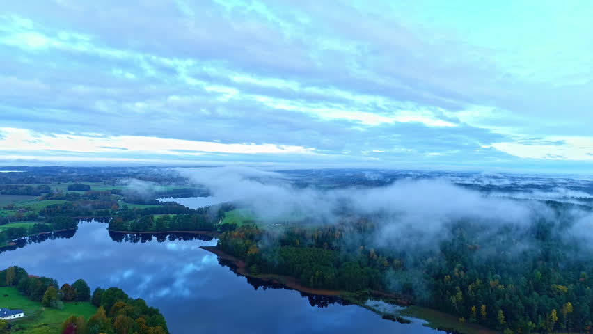 Aerial pullback over calm placid lake with fog mist on forest tree tops