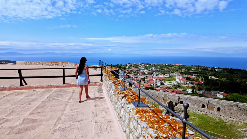 Young, attractive woman overlooking castle walls, the landscape in Greece, and the Mediterranean Sea