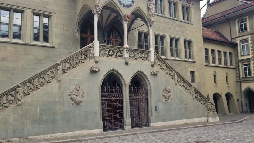 View of Bern’s historic Town Hall (Rathaus) with its late-Gothic sandstone facade, captured on a cloudy spring day. The building serves as a key seat of local government in Switzerland