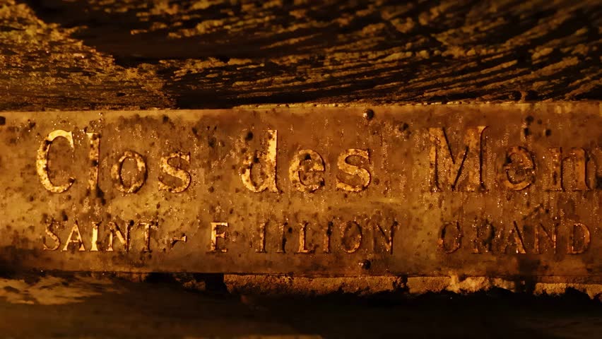 Close-up of a weathered wine cellar sign with rustic textures and dim lighting.