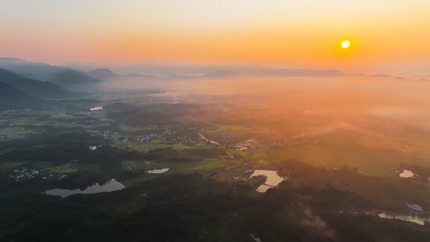 Sunrise over sea of clouds creating a stunning view above farmland villages and rolling hills