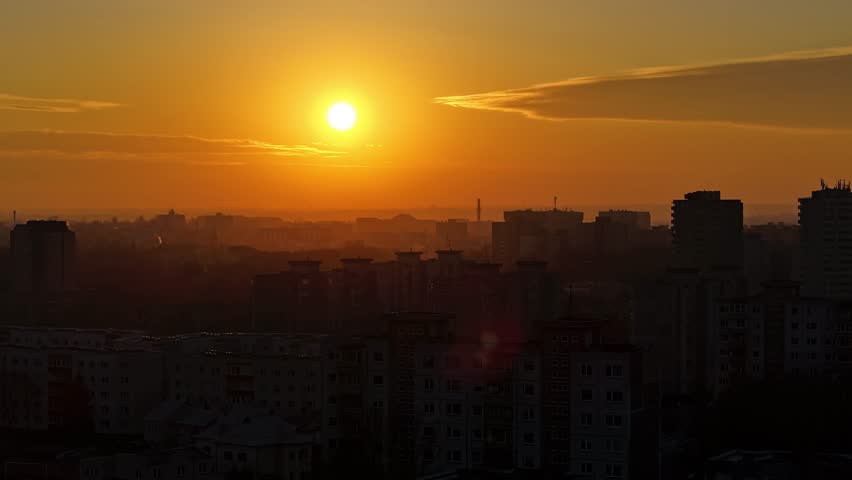 Deep orange sunset over silhouette of Kaunas city buildings, aerial time lapse