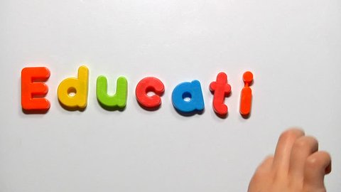 Child's hand writes the word EDUCATION with fridge magnets