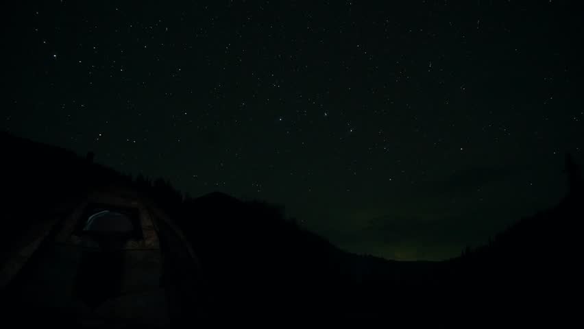 Timelapse of the starry sky on the background of snowy mountains. Lightning flashes and flying meteorites are visible in places. The rotation of the earth against the background of the Milky Way.