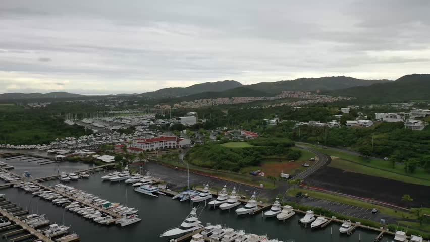 An aerial footage of Safe Harbor Puerto Del Rey filled with boats, with lush hilly shore contains urban buildings on a cloudy day in Puerto Rico