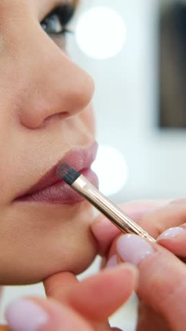 close up Professional lips Makeup, beautician applies lipstick, Beautiful woman face, Hand of make-up master in beauty salon, painting lips, Make up in process 