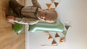 Cute baby boy celebrates 1 year birthday, vertical video. Toddler plays on the floor among balloons and sage green inflatable number one. Child in beautiful costume and festive decor.  - Powered by Shutterstock - Get 15% off with code: PIKWIZARD15