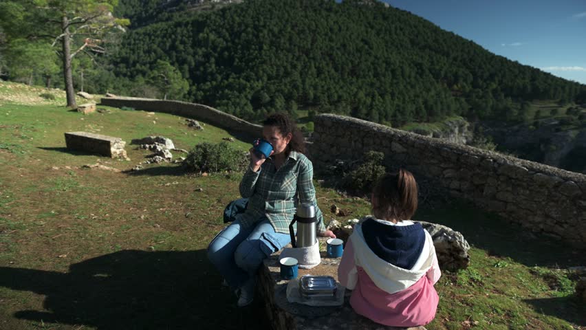 Mountaintop Picnic: Mother and Daughter Enjoy a Sunny Day with Scenic Views
