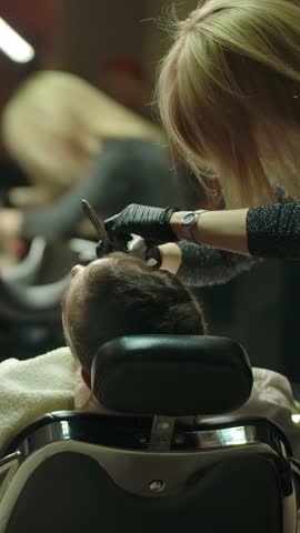 Refocusing from barber with client to open nameplate. Haircut specialists in mall business, modern barbershop, making their job. We are open for each customer now, and ready to make haircut. Vertical