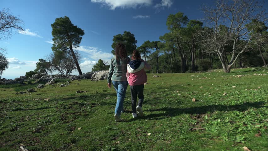 Mother and Daughter Walking Through Picturesque Mountain Landscape