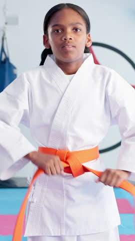 Girl, ready and karate with orange belt for martial arts training, self defense or fighting skill level. Child, taekwondo and warrior challenge with strap or fist for promotion or experience in dojo