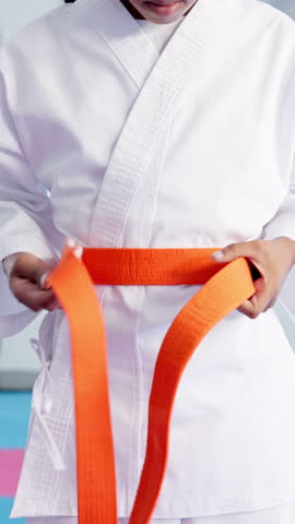Child, hands and karate with orange belt for martial arts training, self defense or fighting skill level. Closeup, taekwondo or fighter getting ready with strap for promotion or experience in dojo