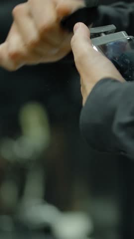 Hairdresser clean his equipment before the arrival of the customer. Close-up of the hands of a professional barber with a brush and trimmer. Vertical shot.