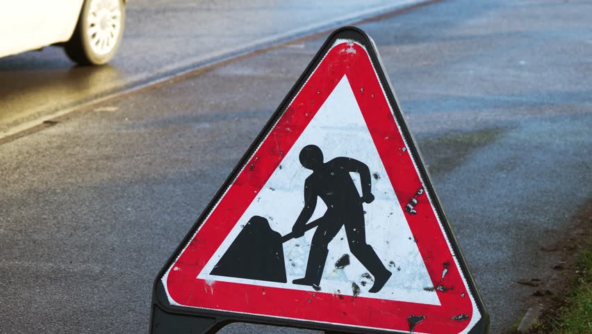 Construction warning sign in United Kingdom. Traffic notice board indicating roadwork ahead in Britain. Road safety marker showing highway maintenance in England