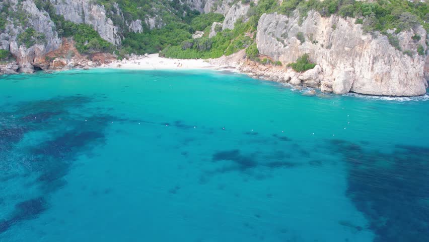 Aerial drone view on white sand Cala Fuili beach of Sardegna Costa Smeralda. Warm turquoise sea and small beach surrounded with green mountains on the Sardinia island.