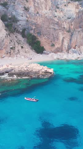 Aerial drone view on white sand Cala Baunei in Orosei Gulf of Sardegna. Warm turquoise sea and small beach surrounded with green mountains on the Sardinia island.