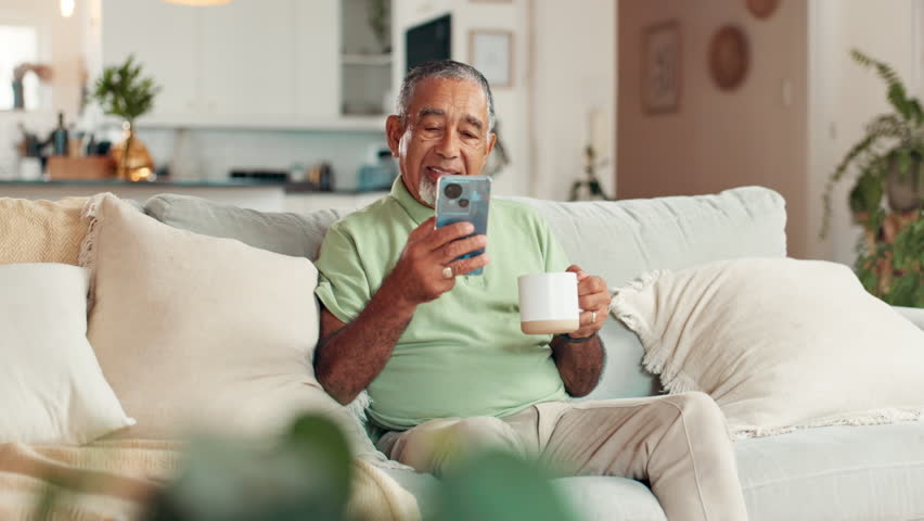 Phone, coffee and senior man on sofa in home with communication, contact or social networking. Relax, cellphone and elderly male person reading online news on mobile app in living room at house.