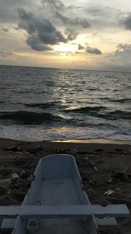 Tranquil Sunset on a Beach: An Abandoned Boat and Ocean Debris Tell a Story of Beauty and Environmental Urgency – Perfect for Eco-Travel, Climate Change Awareness, and Sustainability Campaign