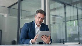 Positive senior businessman entrepreneur sitting at desk working on financial sales project, looking smiling at screen. Mature 50s Latin business man ceo manager using tablet pad computer in office - Powered by Shutterstock - Get 15% off with code: PIKWIZARD15