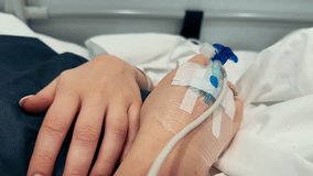 Close-up of an intravenous drip in the hand of a patient lies on bed in the hospital. High quality 4k footage - Powered by Shutterstock - Get 15% off with code: PIKWIZARD15