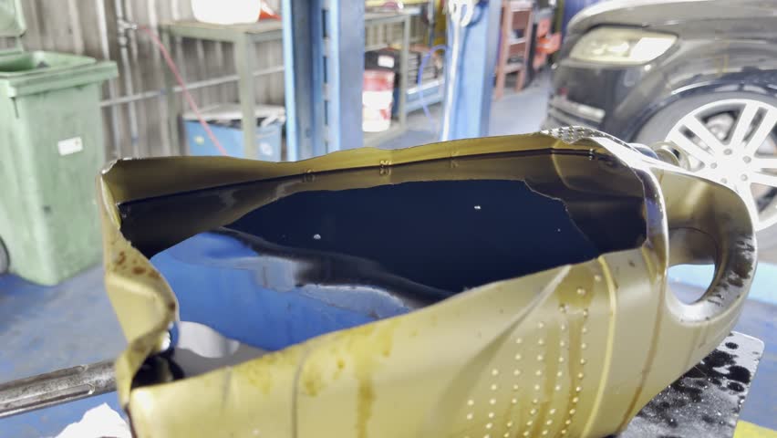 Slow Motion footage of Engine oil drained into a disposal container.