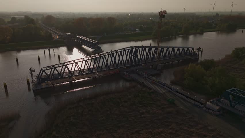 Aerial shot of the new Friesenbrücke railway project near Leer, Germany, at sunset. Massive infrastructure site near Dutch border, crossing the Ems River. Bridge and construction site in golden light.