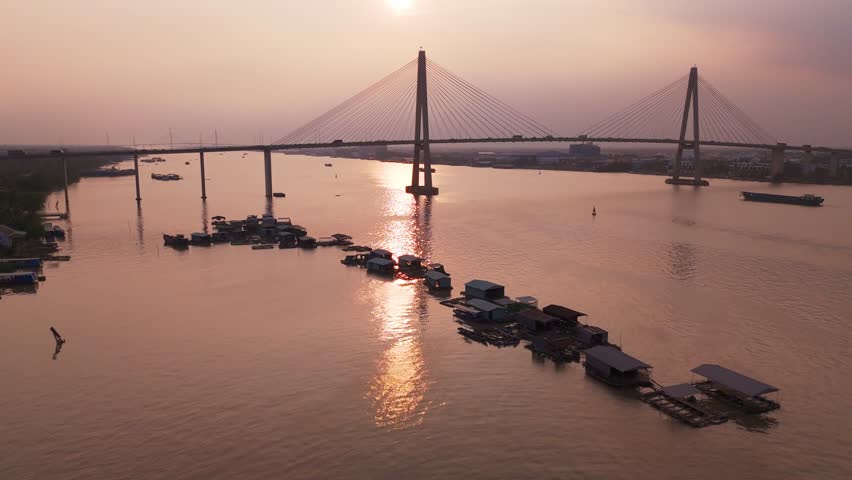 New Rạch Miễu Old and new. Mekong floating housing with new bridge over river. Developing infrastructure of Vietnam shadows the old lifestyle. Drone fly through at sun set.