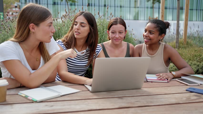 Group of female students, high school pupils gather at University campus, working together on creative task, prepare for final exams using laptop. Girl friends team 