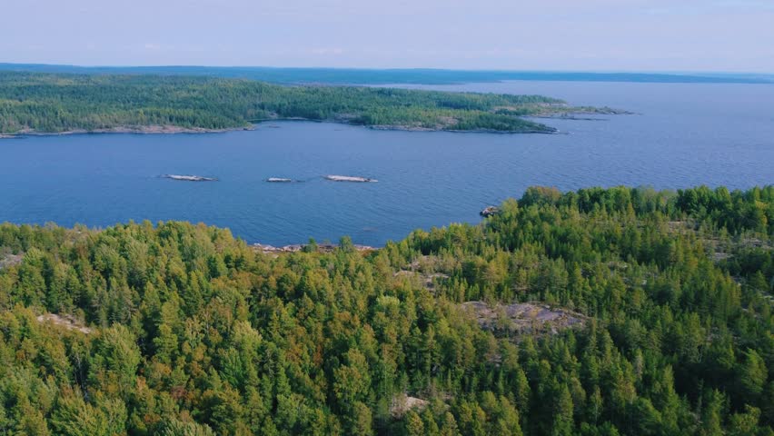 Russia, Lake Ladoga, Koyonsaari. View of the coast of the island in a cold lake. Beautiful nature of the Republic of Karelia. Panoramic view from the height of the Ladoga skerry islands. 4K