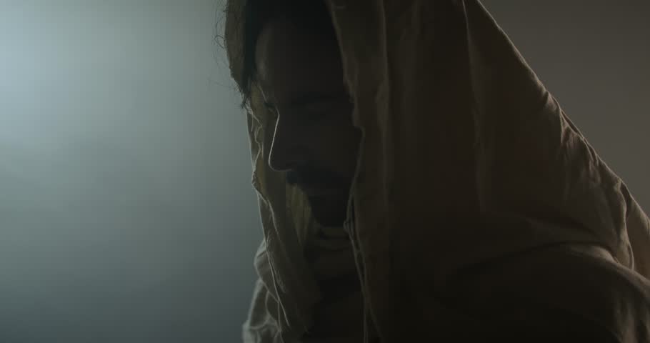 Jesus Christ resurrected on Easter Sunday inside empty tomb in bright, shining light, wearing white hood and robe. Cinematic Christian visual.