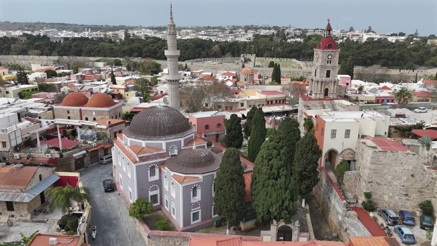 Aerial view slight circular pan left from The Suleyman Mosque and Medieval Clock Tower in the city of Rhodes at Rhodes island in Greece.Old town and the city walls at the background on a sunny day.