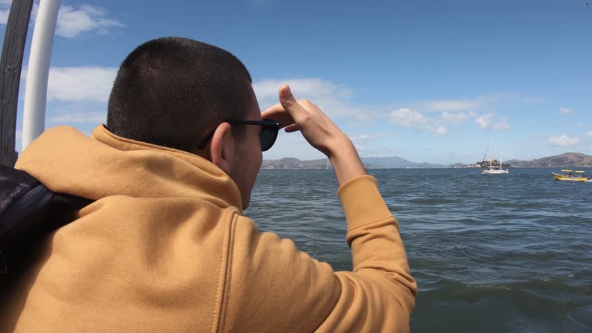 Handsome tourist man enjoying panoramic view of San Francisco Bay with Alcatraz jail island at bacground on a bright day