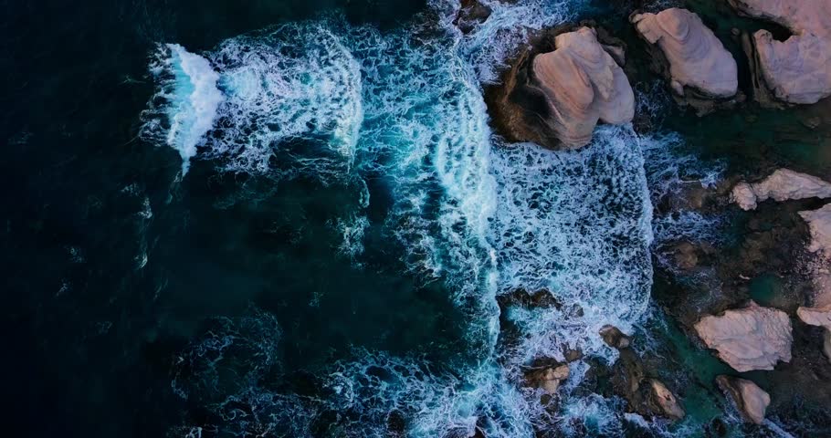 Aerial view of ocean waves crashing into coastal rocks near the Sea Caves in Paphos, Cyprus. Captured in the Mediterranean Sea.Cyprus travel, dramatic nature scenes or Mediterranean coastline footage.
