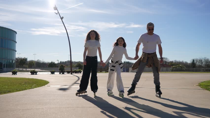 Family members roller skating together, holding hands and gliding smoothly across urban pavement near modern architectural backdrop, sharing joyful moments of outdoor connection and active leisure