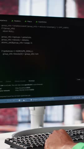 Vertical Video Male programmer types code on computer and running script, programming language. African american IT expert in modern loft fixing errors within the software, implementing new features