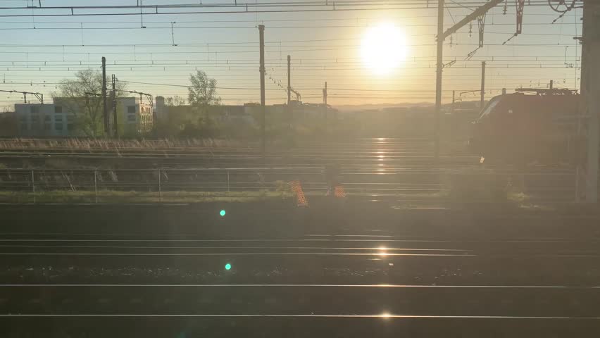 Railroad tracks and wires at sunset as seen from the moving train, France