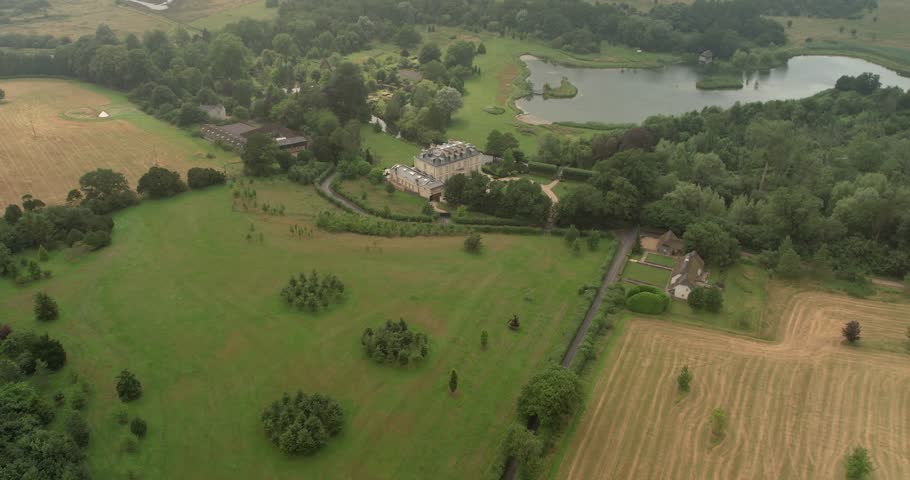 Aerial view flying over Kenwood mansion house with manicured gardens and private lake estate