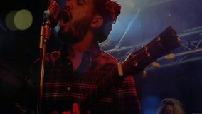 Music performer strumming guitar singing on club stage, showing animated sound waves and neon bars. Performance, live music, rock, acoustic, night, concert, dramatic - Powered by Shutterstock - Get 15% off with code: PIKWIZARD15