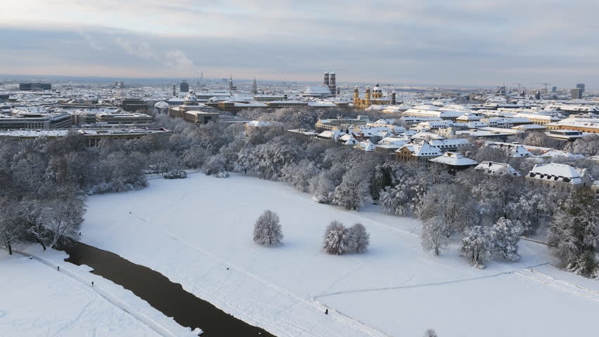 Aerial view of the Englischer Garten in Munich with the Frauenkirche and Theatinerkirche in the background. In winter, with lots of snow.