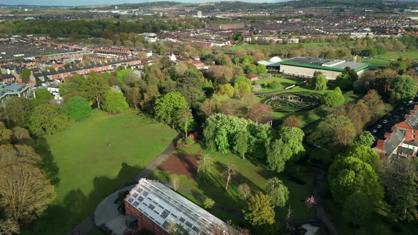 Ultra-wide, forward travelling aerial of Botanic Gardens and the Palm House in Belfast, County Antrim in Northern Ireland on a sunny day. Filmed in 4K, 60FPS and in Rec709 Color.