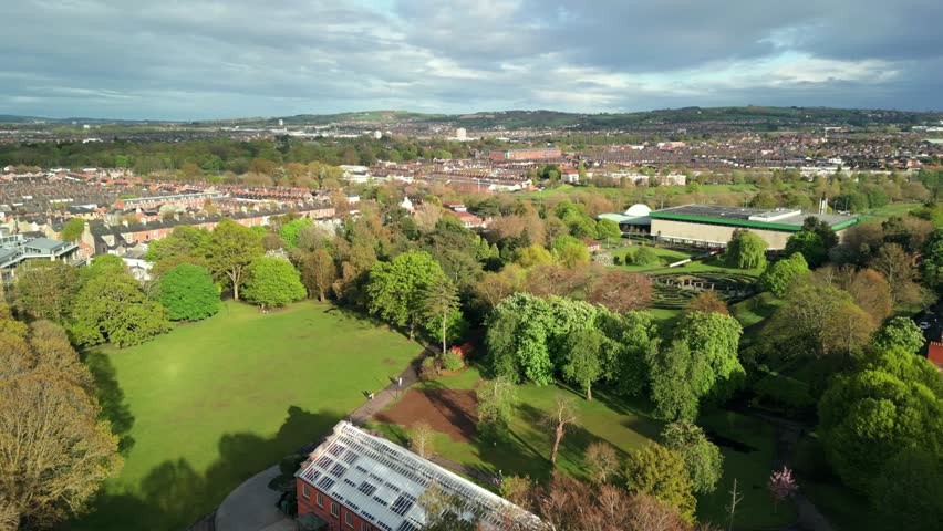Wide, forward travelling aerial of Botanic Gardens and the Palm House in Belfast, County Antrim in Northern Ireland on a sunny day. Filmed in 4K, 60FPS and in Rec709 Color.