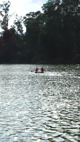 unrecognizable people using a row boat in a lake, outdoors activity, couple rowing wearing safety life jacket on a rented rowboat, summer vacations in nature